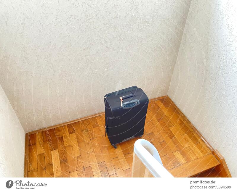 Someone must have left a black wheeled suitcase in a stairwell. Photo: Alexander Hauk Suitcase travel vacation staircases Staircase (Hallway) rail Brown White