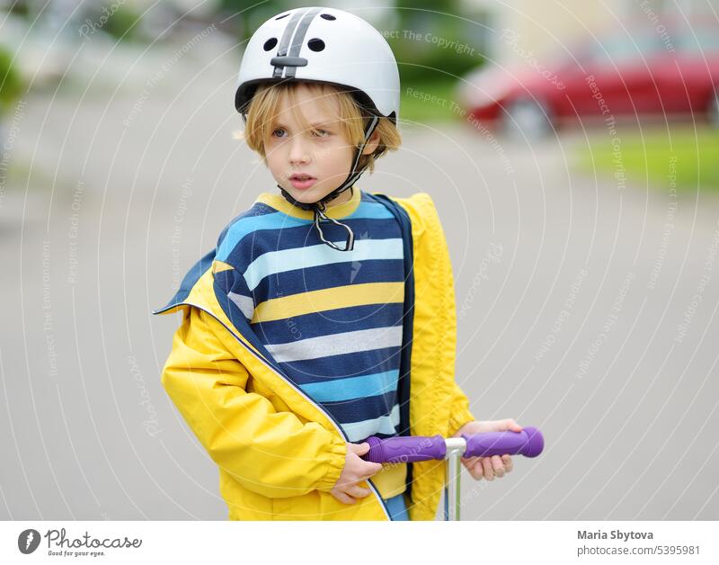 Little boy in safety helmet is riding scooter. Child is bored without friends. kid street traffic child ride city caucasian childhood children family fun
