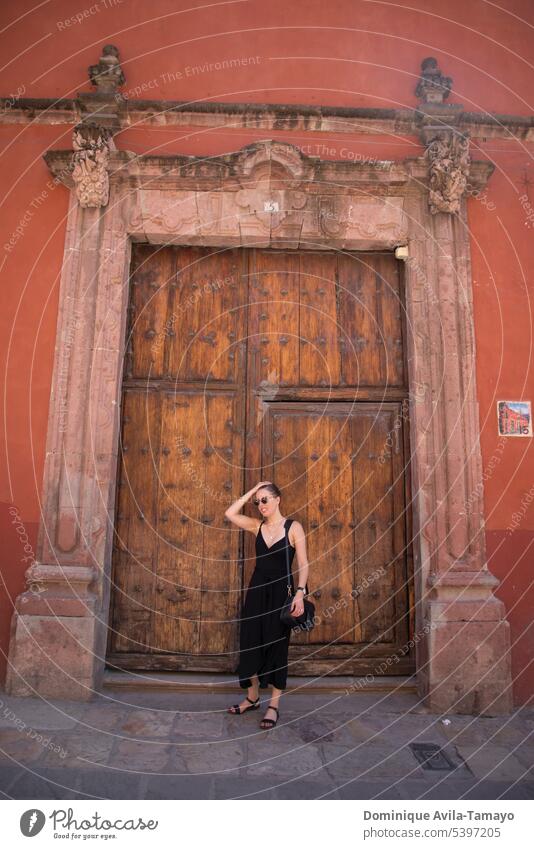 Woman wearing black dress in front of wooden door woman yound posing Old Entrance Exterior shot Closed Front door Wooden door young woman travel adventure