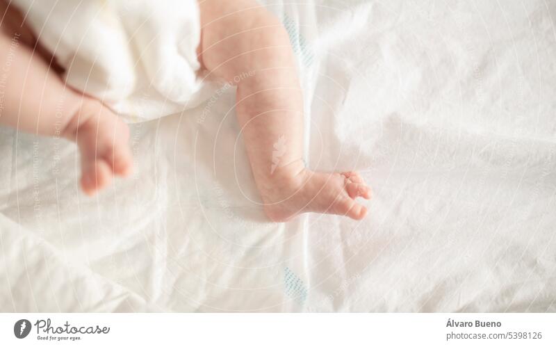The little legs and feet of a newborn baby in a diaper, in the crib, at home premature view subjective little feet little fingers tenderness tucked bed underpad