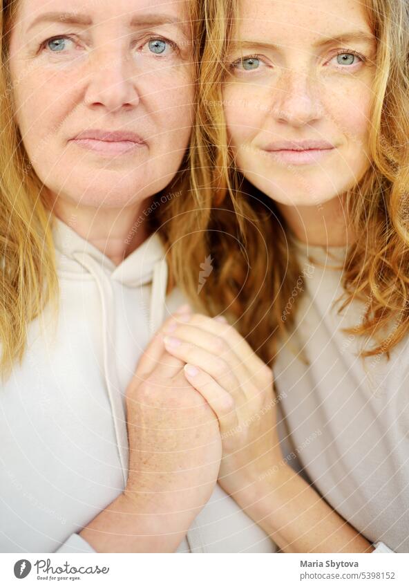 Redhead senior mother and her beautiful adult daughter are embracing. Family relationships between adult children and older parents. Close-up portrait of two generations of family.