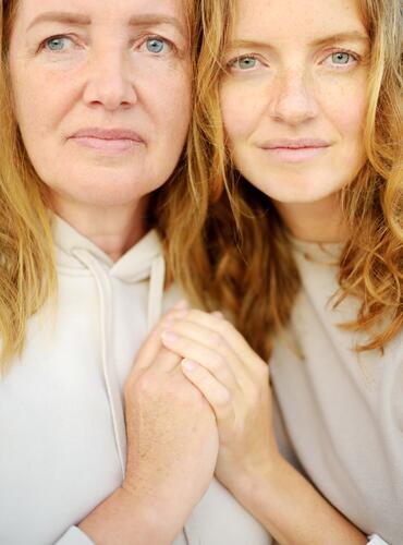 Redhead senior mother and her beautiful adult daughter are embracing. Family relationships between adult children and older parents. Close-up portrait of two generations of family.