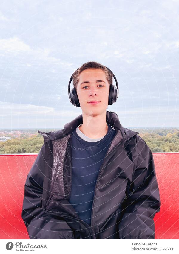 Teen in Ferris wheel with headphones teenager Headphones Music Listen to music Joy Technology youthful Lifestyle Boy (child) Smiling Brunette