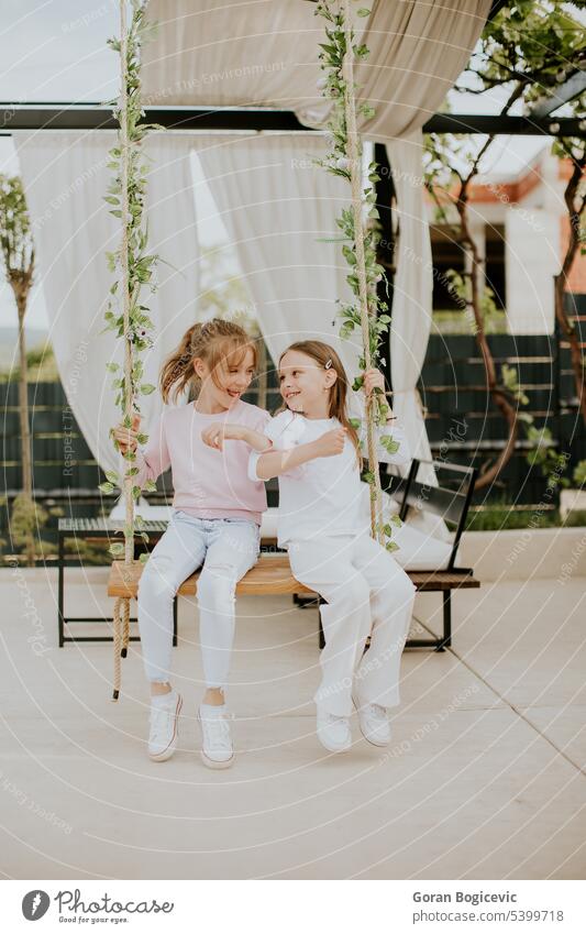 Cute little girls on the swing in the house backyard children childhood people portrait home fun happy happiness pretty female white lifestyle cute smile family