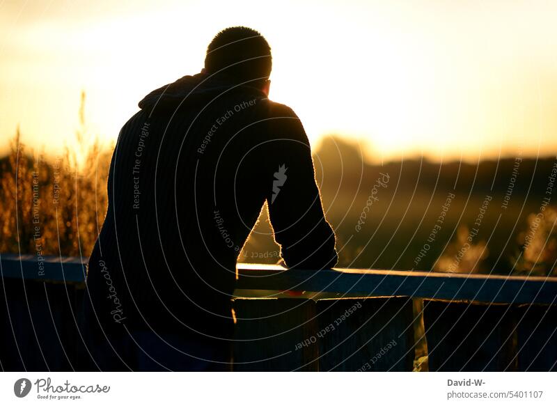 Man looks into the distance and enjoys the peace and the last rays of sunlight of the day Far-off places silent tranquillity To enjoy Sunset Sunbeam Sunlight