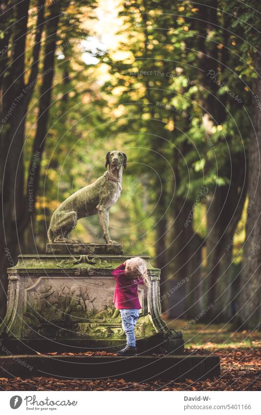 Toddler looks at statue in awe reverence Child Cute Statue explore inquisitorial spellbound impressed Girl Past Dog Observe Infancy inquisitive