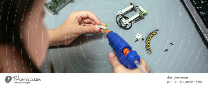 Student using hot melt glue gun on machine pieces in robotics class unrecognizable student female child electronic circuit electrical banner panoramic web