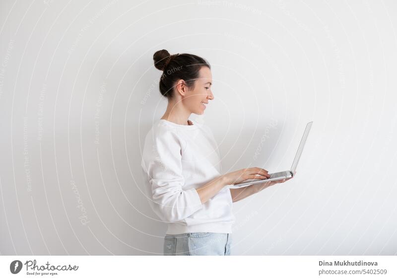 Young woman holding laptop, working. Millennial person in white sweatshirt on white background. People using technology. beautiful business call caucasian