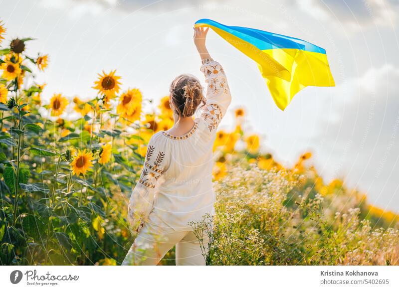 Young ukrainian woman waving national flag on sunflowers, wheat field background freedom girl independence outdoors patriot patriotic patriotism symbol ukraine