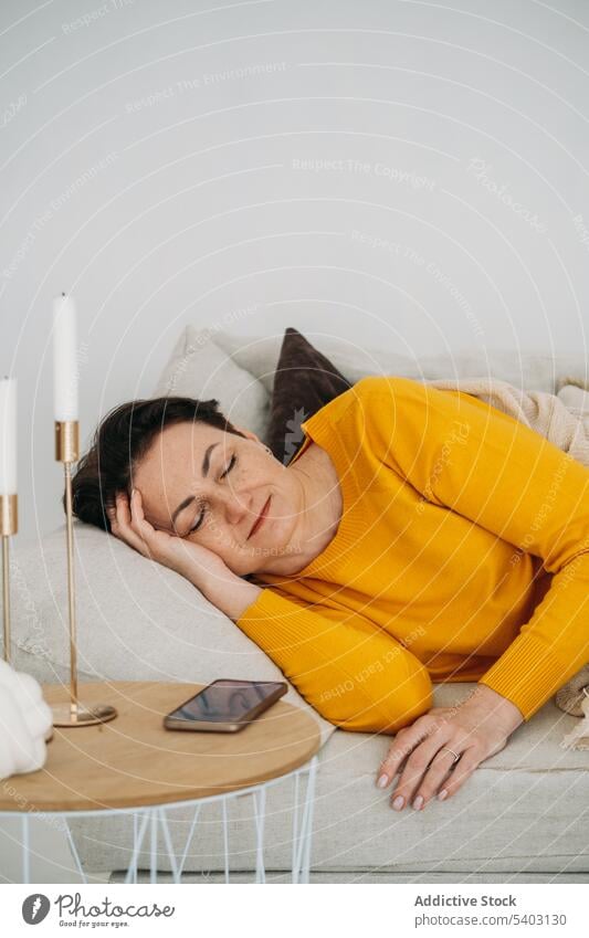 Mature woman sleeping on sofa calm nap rest relax living room home comfort couch serene lying tranquil chill female peaceful asleep casual lounge apartment lazy