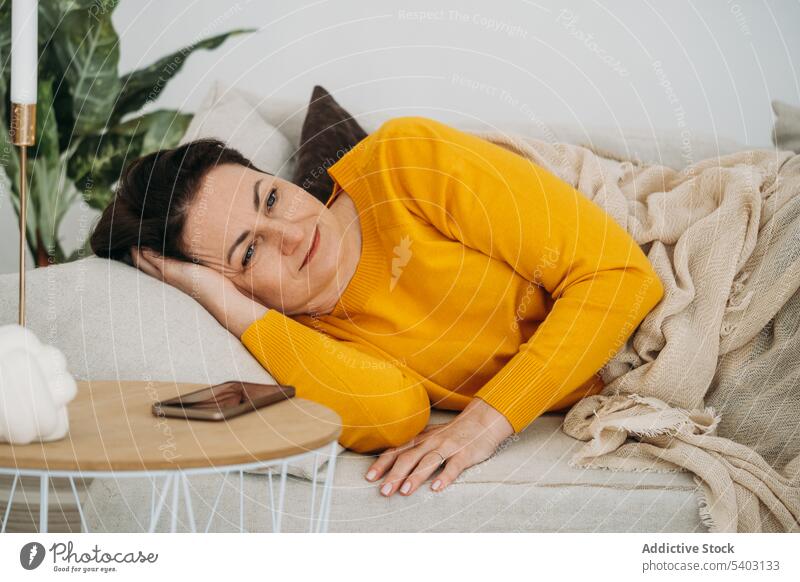 Mature woman resting on sofa calm nap relax living room home comfort couch serene lying tranquil chill female peaceful casual lounge apartment lazy middle age