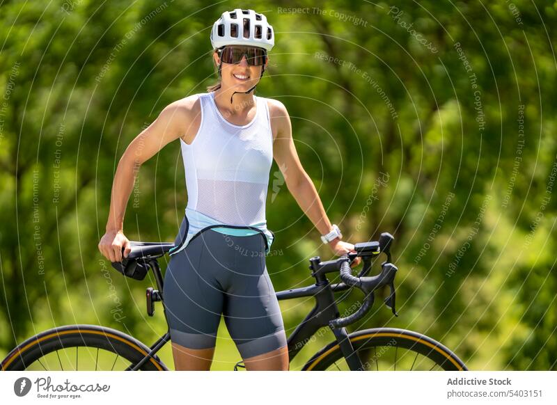 Sportswoman with bicycle against blurred park sportswoman athlete bike helmet sunglasses sportswear fit portrait female bicyclist activity dynamic cardio