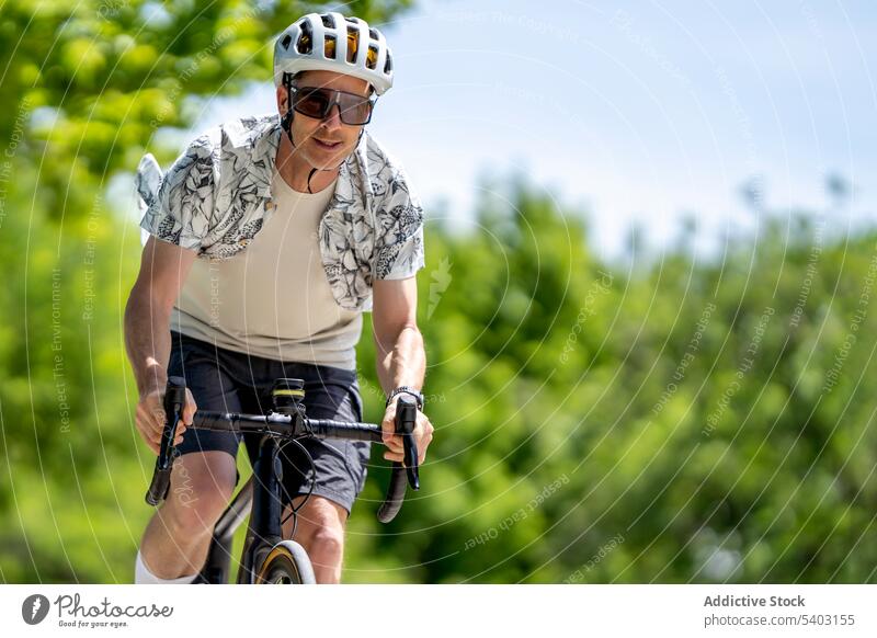 Sportsman on bicycle on countryside against blurred background sportsman bicyclist ride helmet sunglasses park summer male athlete active dynamic speed fast