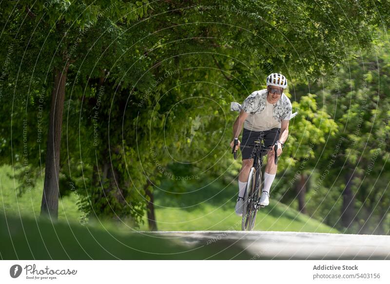 Sportsman on bicycle on countryside against blurred background sportsman bicyclist ride helmet sunglasses road park summer male athlete active dynamic speed