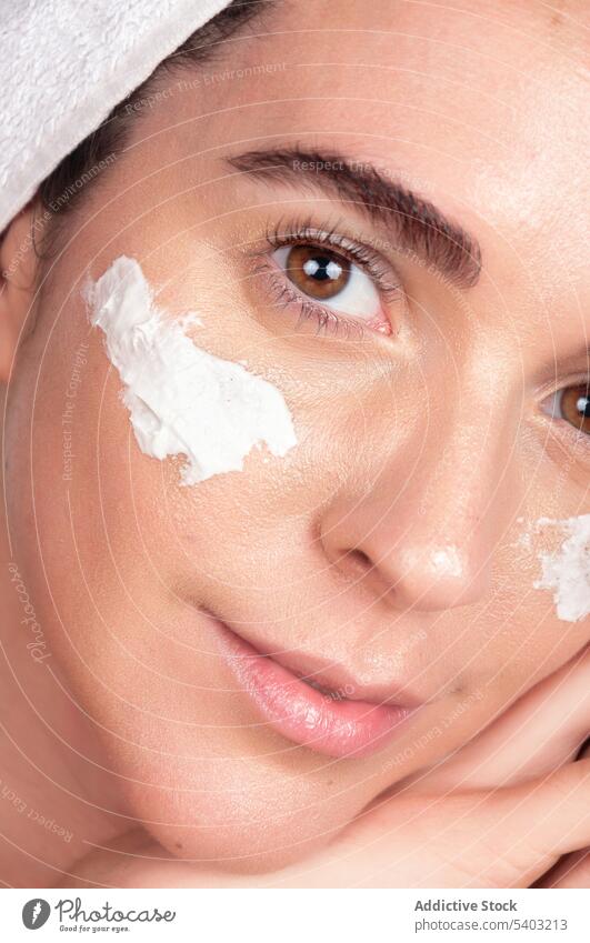 Happy crop young woman with white face mask and cream skin care smile procedure cosmetic apply towel moisture female cosmetology relax facial wellness beauty