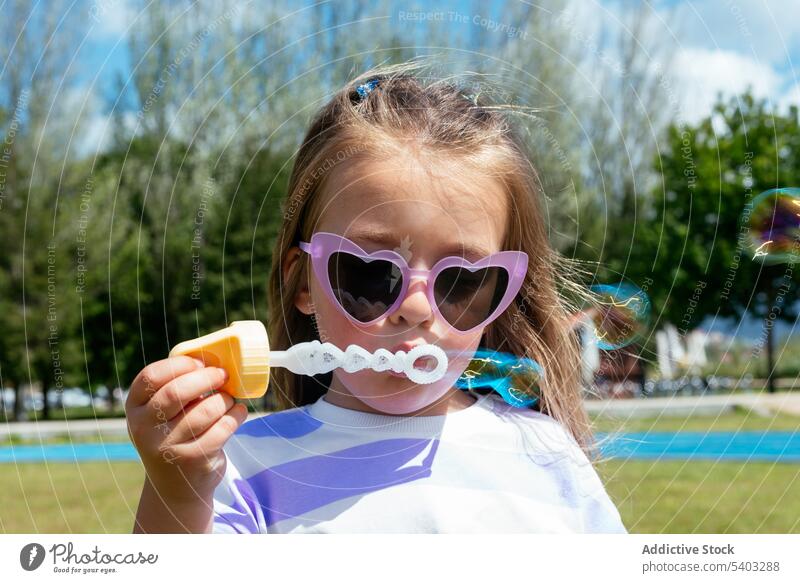 Little girl blowing bubbles in park soap bubble kid play lawn toy childhood adorable little grassy sunglasses cute playful fun activity enjoy innocent