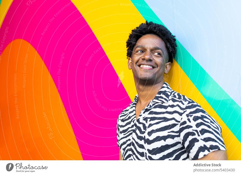 Cheerful young man near multicolored wall positive smile portrait stripe colorful confident happy style glad black african american curly hair cheerful male