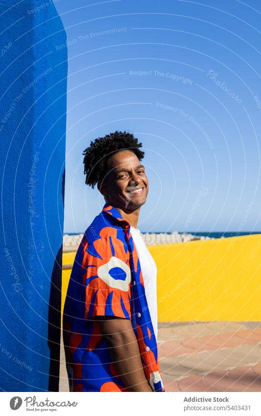 Happy young man in stylish clothes cheerful shirt happy positive wall urban glad outfit style smile black african american male content ethnic colorful fashion
