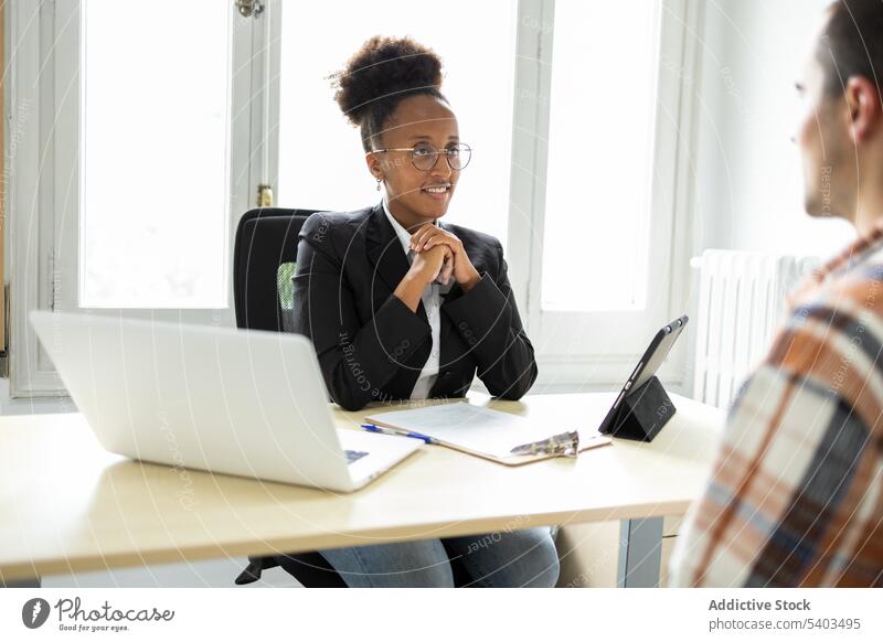 Focused black woman legal adviser discussing with client at table lawyer interact work professional smile office young female african american ethnic eyeglasses