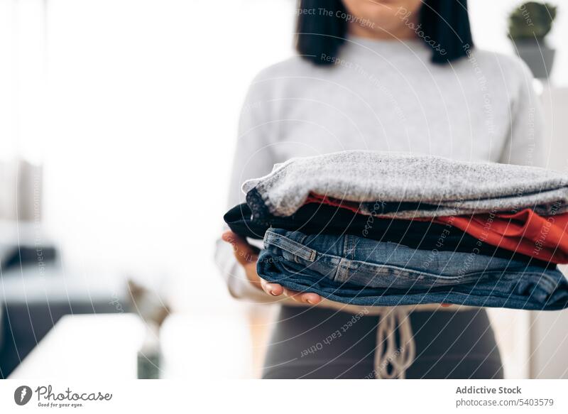 Unrecognizable woman carrying folded clothes clean clothing cotton domestic dress hand heap homemaker housework laundry material pile preparing shirt sweater