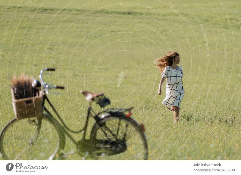 Woman walking carefree on green field with wind blowing woman bicycle park meadow summer nature adventure active activity young alone enjoy grass female freedom