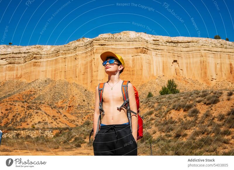 Teenage boy in sunglasses with backpack in desert traveler tourist adventure kid canyon vacation mountain hill cliff rojo teruel teenager nature journey edge