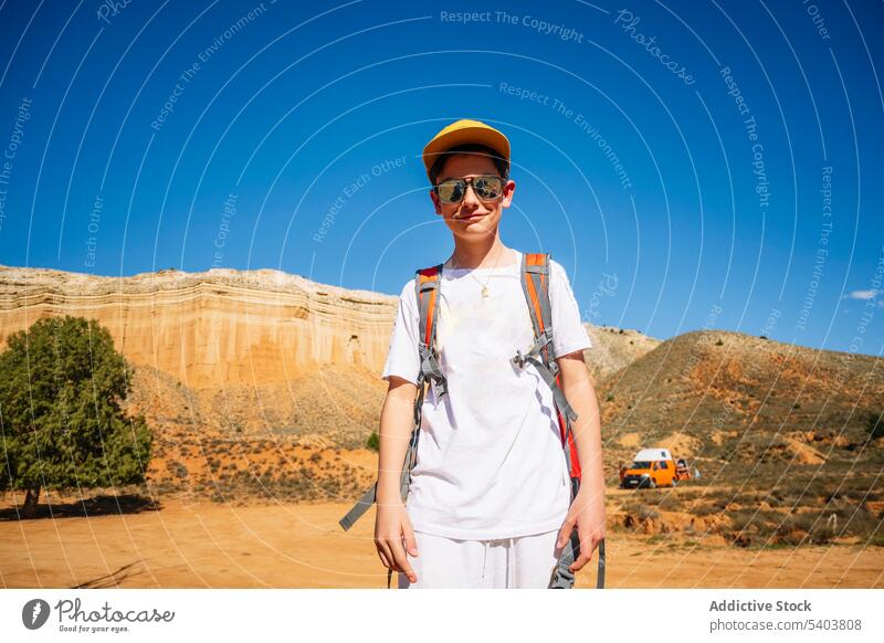 Teenage boy in sunglasses with backpack in desert traveler tourist adventure kid canyon vacation mountain hill cliff teenager rojo teruel nature tree journey