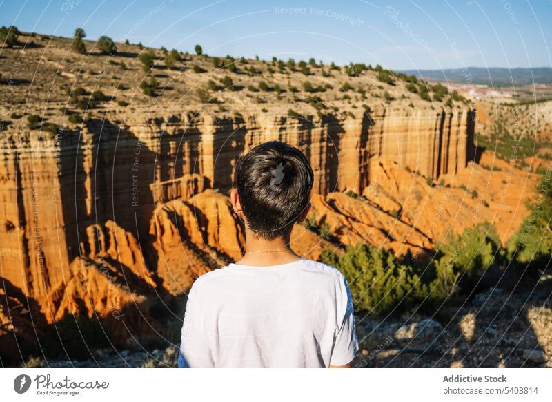 Unrecognizable traveler above majestic mountains boy anonymous backpack freedom canyon cliff shadow male vacation casual rojo teruel adventure guy trip teenager