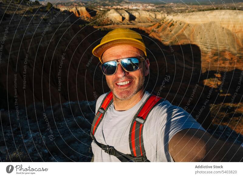 Happy male hiker in sunglasses taking selfie on rocky cliff man traveler canyon smile portrait self portrait happy rojo teruel positive vacation casual