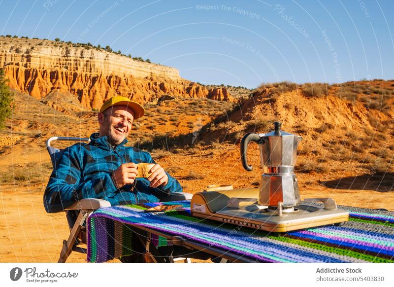 Man drinking hot beverage in canyon mountains man coffee rest camp tourist cup kettle hot drink chair desert adventure morning rojo teruel male relax sit