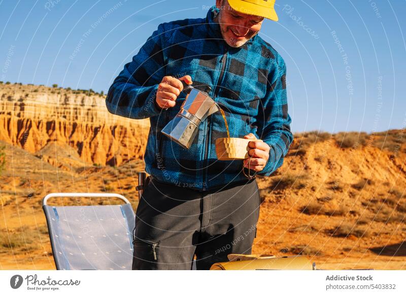 Happy man pouring coffee from kettle in countryside traveler cheerful canyon moka pot tourist smile portrait happy rojo teruel trip drink stand mature positive