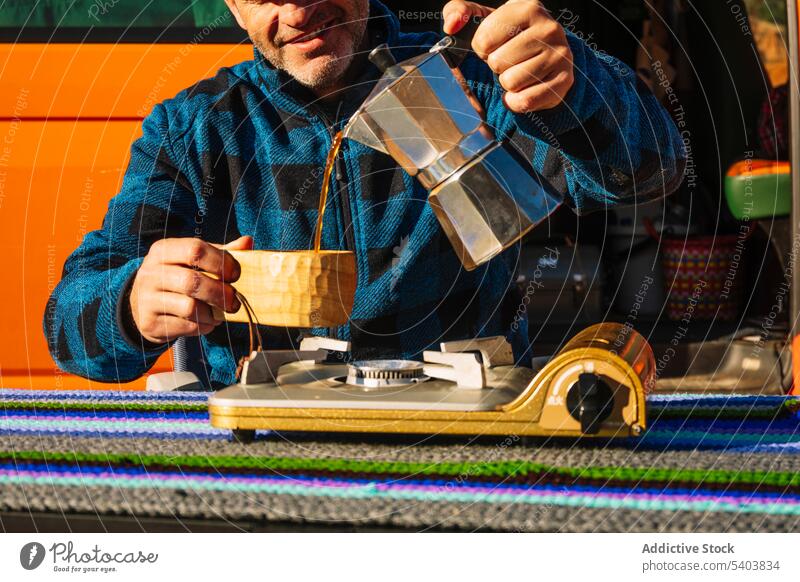 Crop happy tourist pouring coffee from moka pot man van camper drink smile campsite canyon travel stove nature cup vacation brew traveler rojo teruel morning