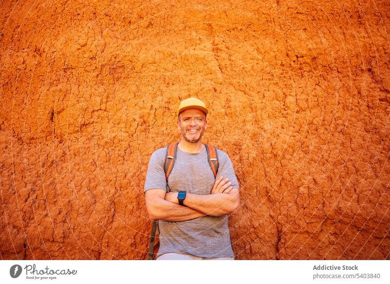 Positive man at arms across standing by sandstone happy tourist traveler thoughtful limestone tourism canyon journey vacation old destination casual explore