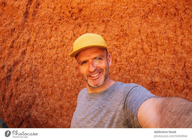 Cheerful man in cap taking selfie near canyon wall smile portrait tourist vacation tourism traveler journey adventure rojo teruel shirt cheerful male happy