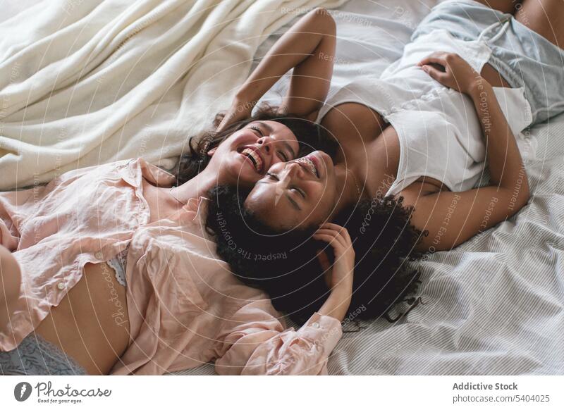 From above of diverse girlfriends in love with each other lying on bed couple lesbian relationship romantic relax blanket eyes closed happy homosexual lgbt