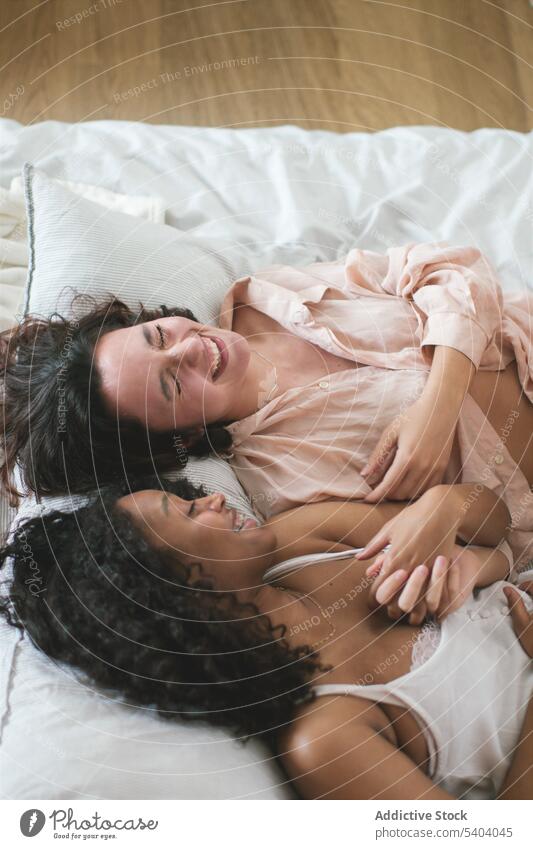 Diverse girlfriends in love with each other lying on bed couple lesbian relationship romantic relax blanket eyes closed happy homosexual lgbt together fondness