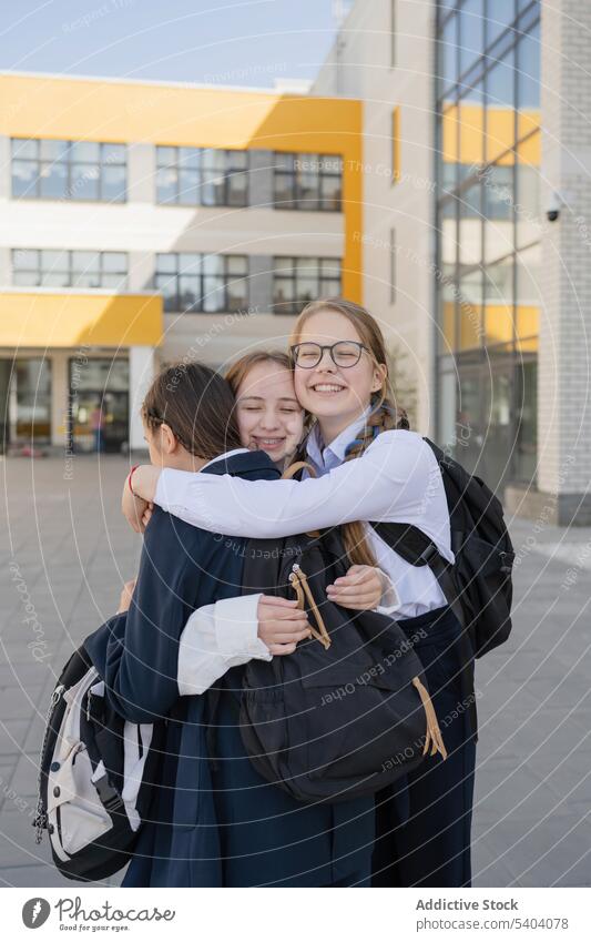 Happy young teenage girls hugging on school campus friend classmate adolescent student schoolgirl building smile friendship pupil happy backpack positive
