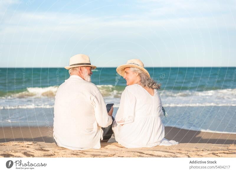 Romantic senior couple spending time on coast love beach romantic sunset together vacation close summer straw hat sundown elderly mobile seashore evening