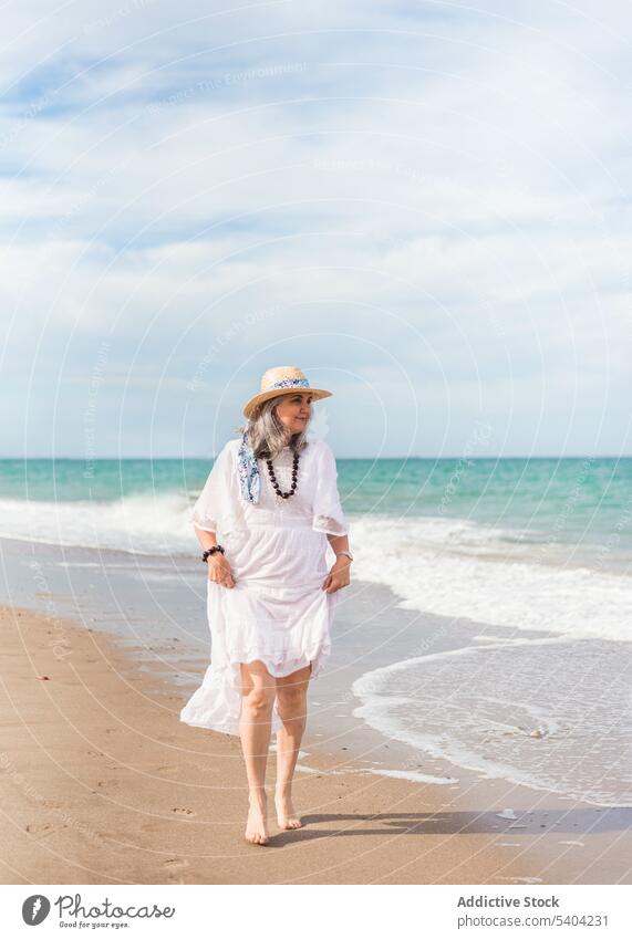 Happy woman walking on sandy beach happy freedom enjoy vacation summer sea nature elderly senior pensioner aged shore wave water seashore coast female ocean