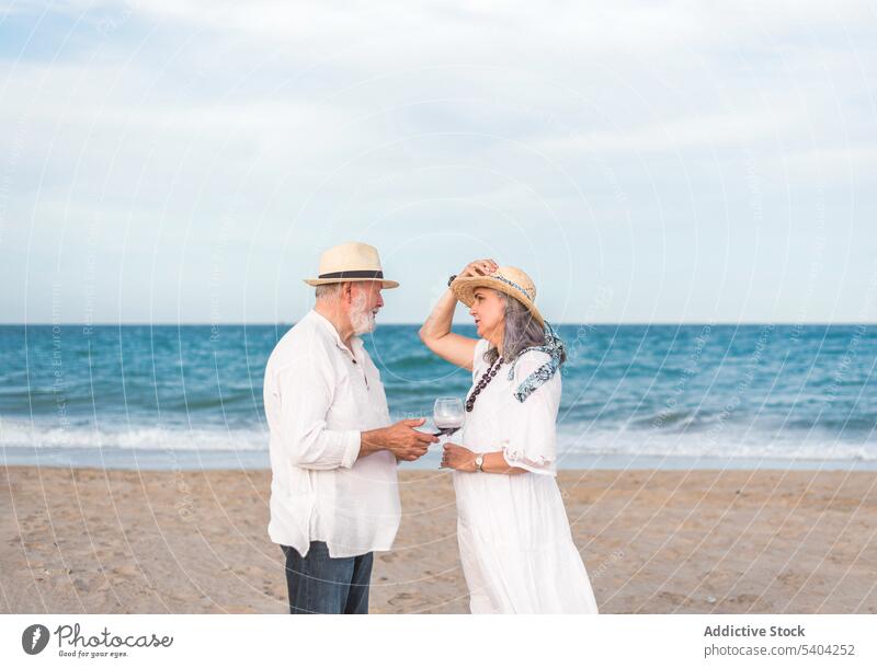 Relaxed senior couple with wine on beach leisure romantic ocean sea listen relationship together drink vacation summer love idyllic aged water pensioner coast