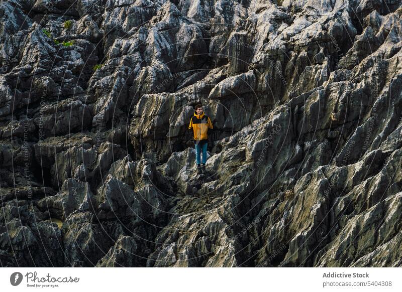 Male hiker standing on rocky mountain slope man traveler adventure cliff explore highland spain nature male summer vacation landscape wanderlust distant