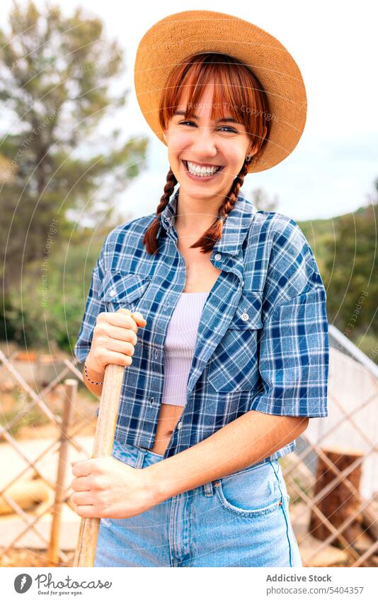 Cheerful woman with hat in garden countryside fence smile cheerful positive nature casual leisure relax weekend wooden young female rest rural joy glad trendy