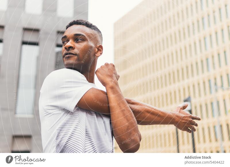 Black man stretching arms on street athlete warm up exercise workout sportswear city skyscraper male black african american fitness training physical activity