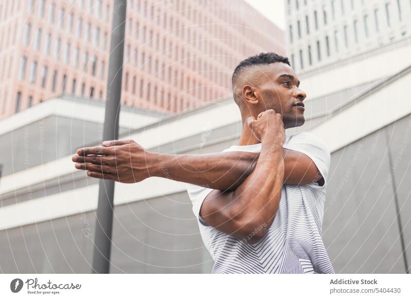 Black man stretching arm on street athlete warm up exercise workout sportswear city male black african american fitness training physical activity aerobic