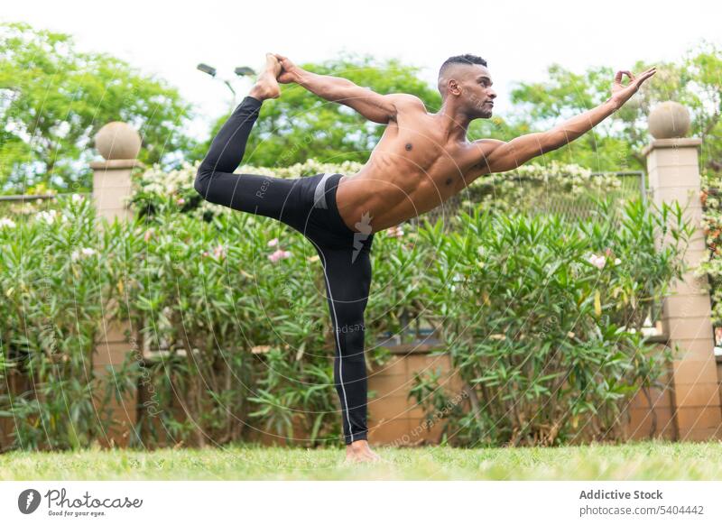 Black calm man doing yoga in Dancer Pose athlete natarajasana pose stretch leg gyan mudra tropical male black african american balance bend breathe practice