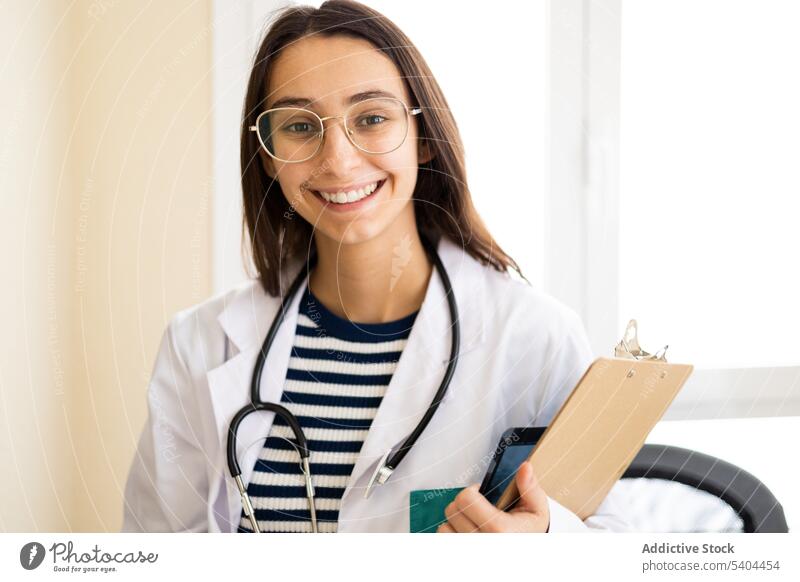 Smiling woman with clipboard and stethoscope doctor uniform smile professional medicine portrait clinic specialist positive healthcare young work medical