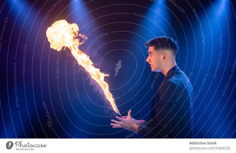 Man showing trick with fire man prestidigitator burn flame magic perform circus stage male magician illusionist fakir pyrotechnics blaze ignite juggler conjure