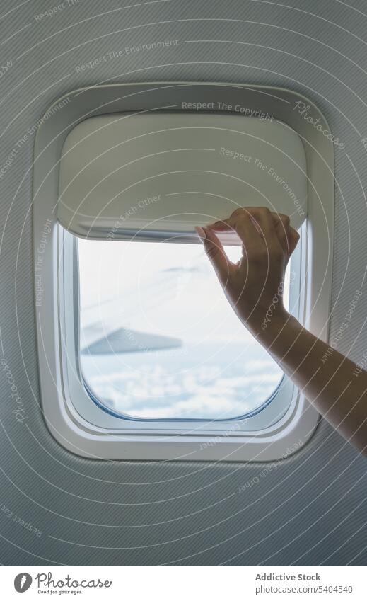 Unrecognizable passenger opening blind in aircraft journey window shadow flight trip travel vacation tourist tourism destination plane traveler voyage aviation