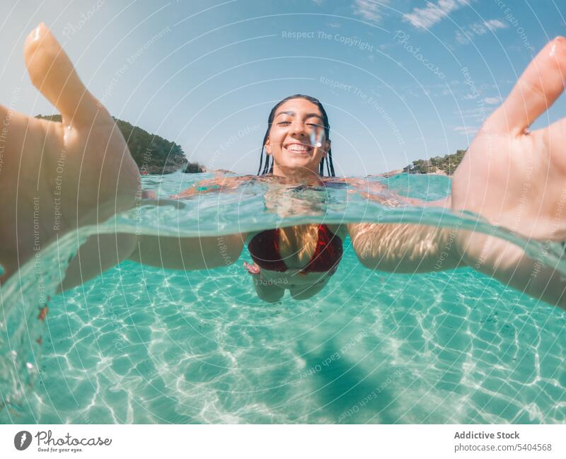 Woman taking selfie while swimming woman float bikini sea summer self portrait tropical resort female balearic islands take photo memory moment swimwear