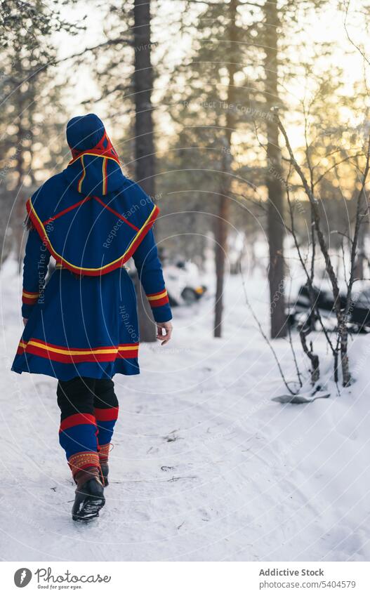 Unrecognizable indigenous person in gakti and nutukas in winter woodland saami authentic forest snow countryside walk native season cold nordic frost wintertime